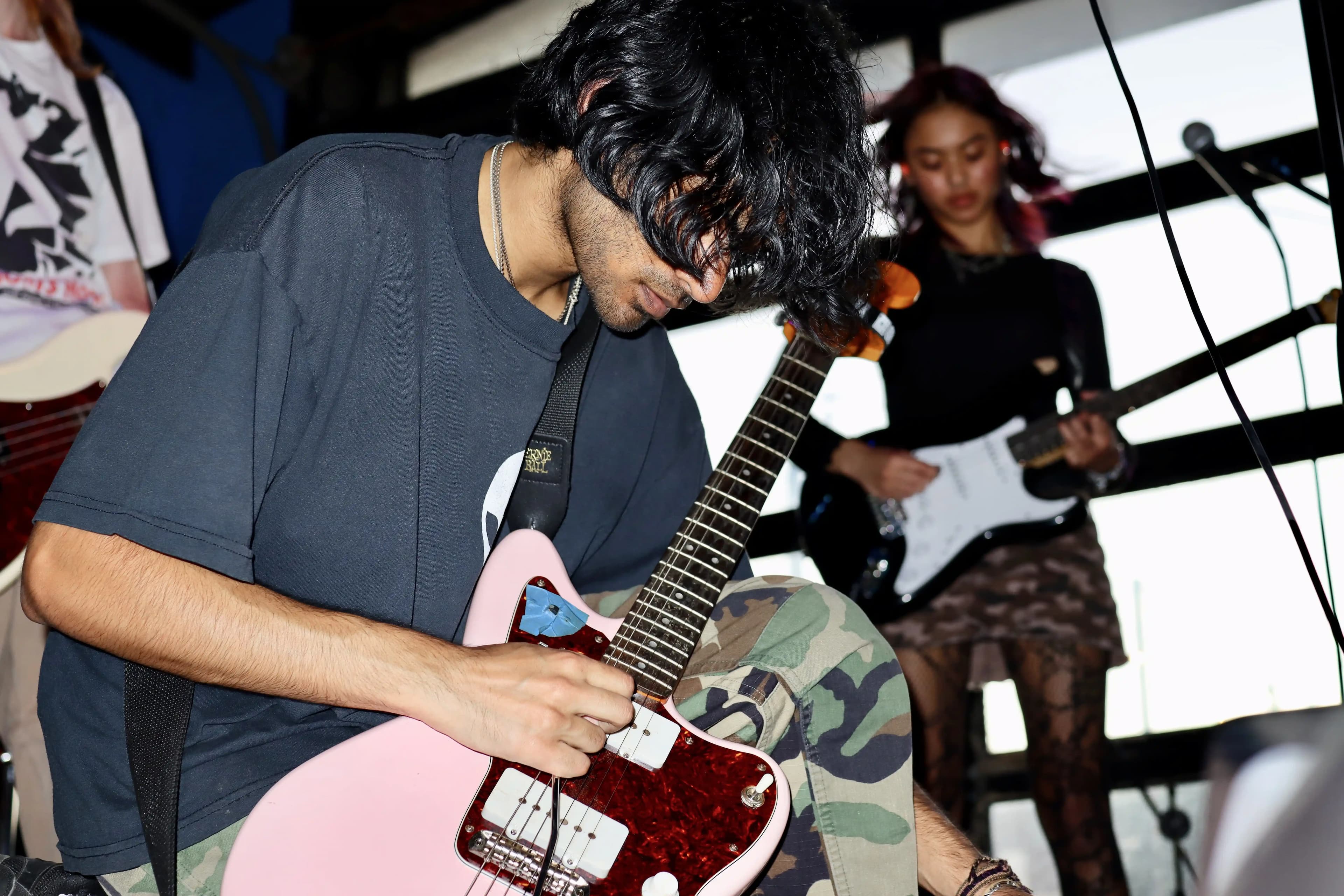 Two KANM members performing guitar on stage at a live music venue.